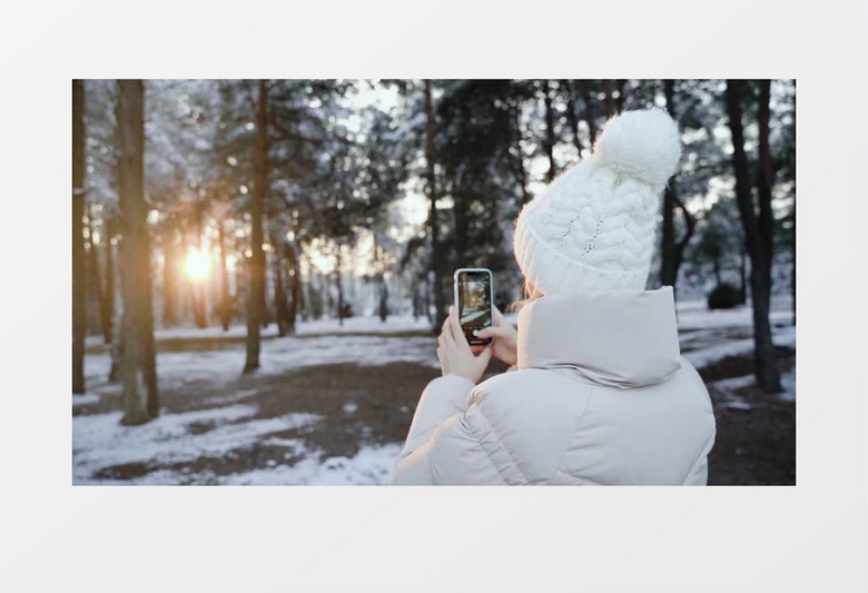 带着帽子的女人拿着手机在树林里拍照实拍视频素材
