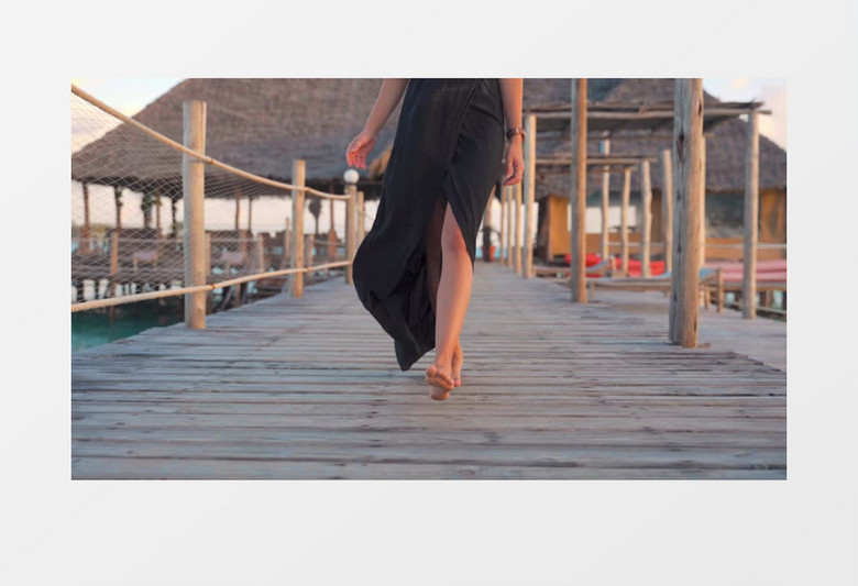性感的女人穿着黑色裙子走在海边的小桥上实拍视频素材