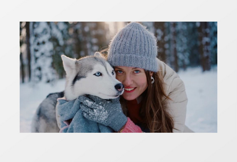 女人抱着宠物狗在树林中的雪地里实拍视频素材