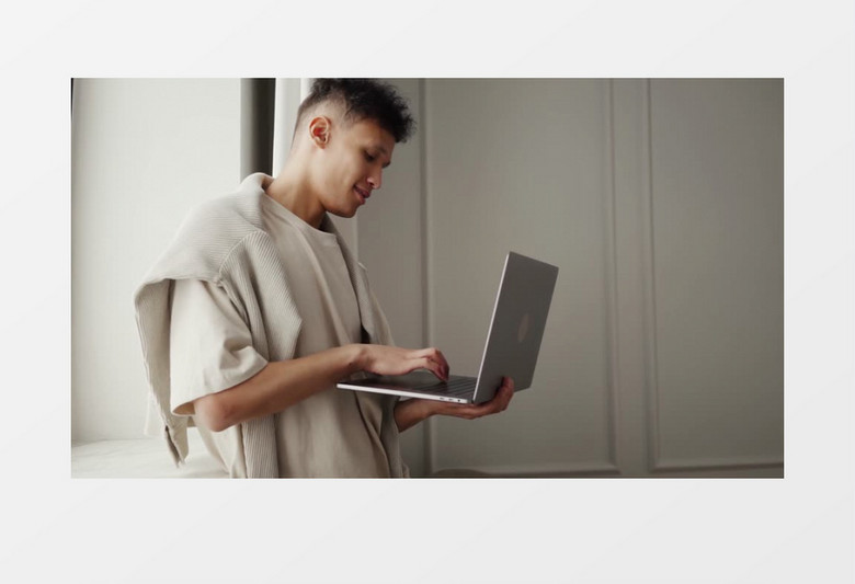 男人拿着笔记本电脑站在窗前打字实拍视频素材
