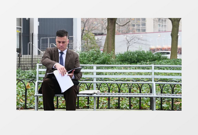 男人坐在路边的长椅上翻看报表实拍视频素材