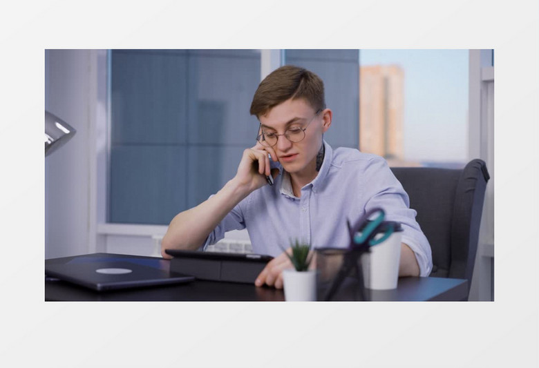 男人坐在办公桌前边喝咖啡边打电话实拍视频素材