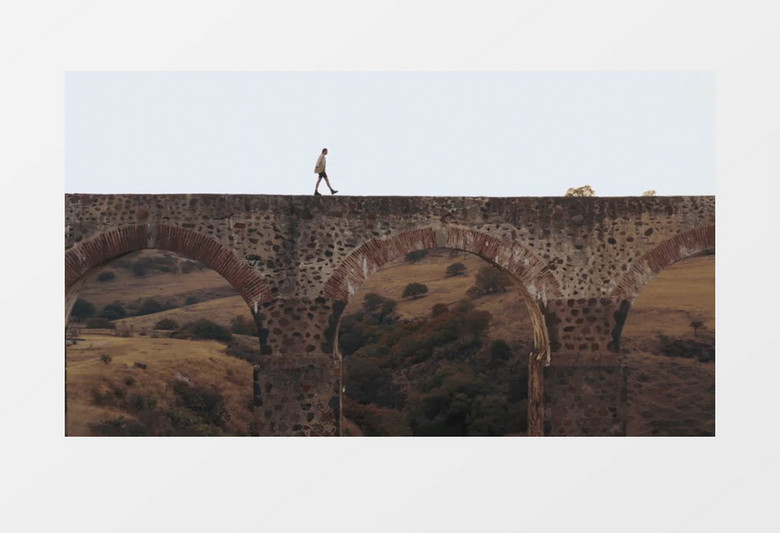 高清拍摄男子走在石拱桥上实拍视频素材