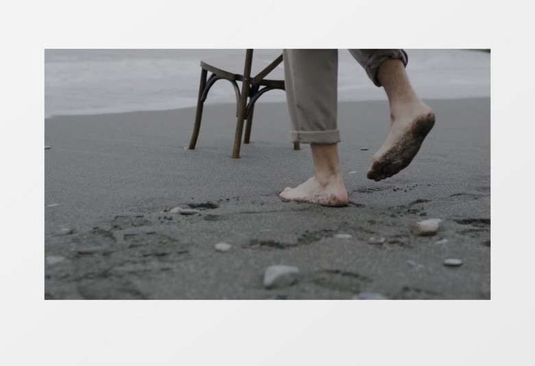 男子光脚坐在沙滩的椅子上实拍视频