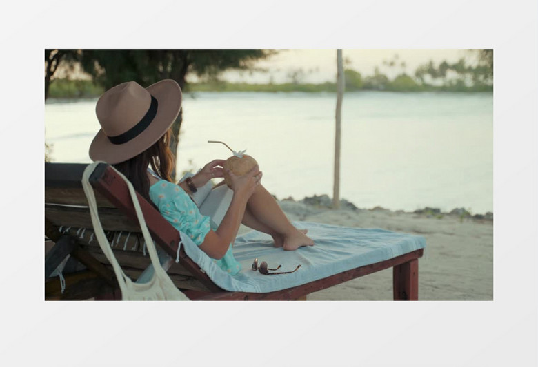 女孩在海边上的躺椅喝椰汁实拍视频