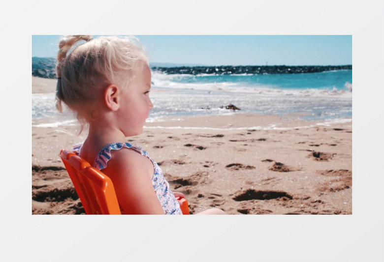 金色头发的小女孩坐在海滩上看风景实拍视频