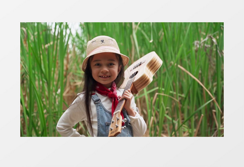 小女孩拿着吉他站在芦苇丛实拍视频素材