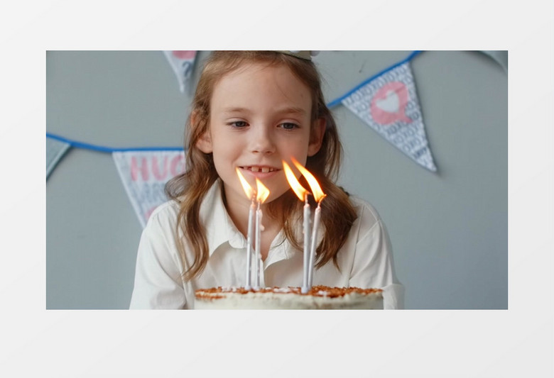 女孩在对着点燃生日蜡烛的蛋糕许愿实拍视频素材