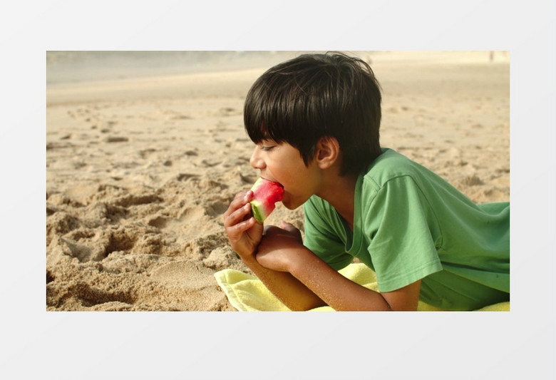 小男孩趴在沙滩上吃西瓜实拍视频素材