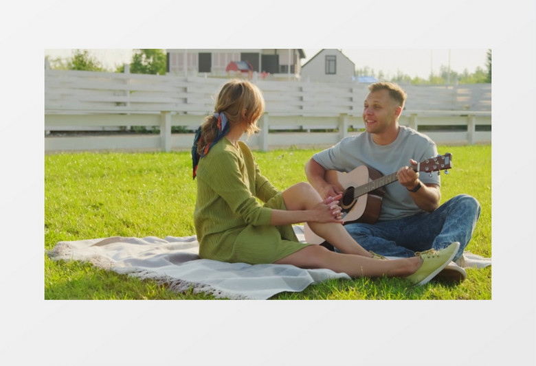 男子坐在草地上给女人弹吉他唱歌实拍视频素材