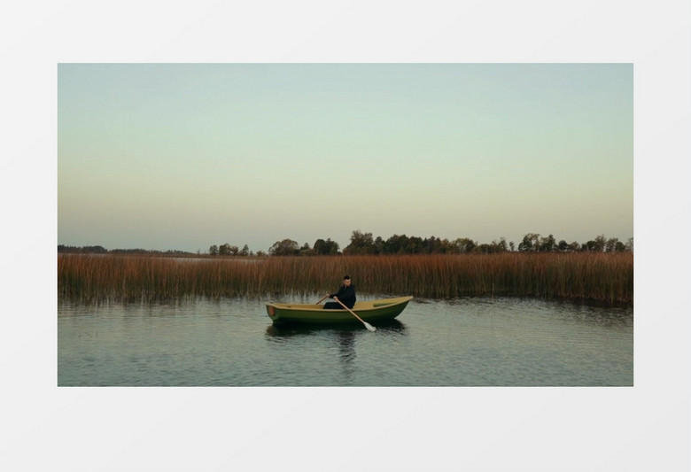 一个男人在平静的水面上划船实拍视频素材