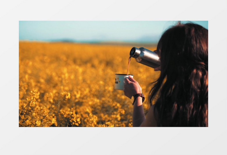 一个女孩在油菜花田旁倒水实拍视频素材
