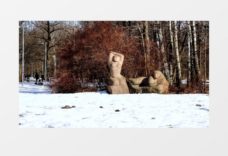 雪林里有两个雕像以及树林中玩耍的人群实拍视频素材